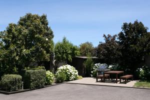 a picnic table and benches in a garden at Alpine Lake Motel in Taupo