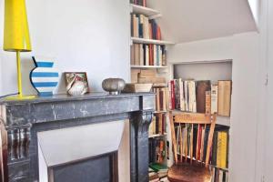 a fireplace with a chair next to a book shelf at Very Nice Apartment Between Pigalle And Montmartre in Paris