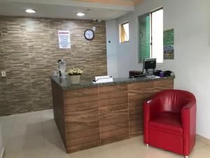 a red chair sits in front of a reception desk at Hotel Oliveira in Goiânia