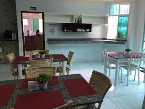 a dining room with tables and chairs and a kitchen at Hotel Oliveira in Goiânia