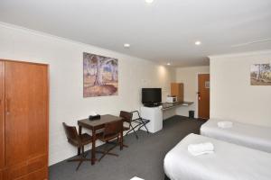 a hotel room with a bed and a table and a bedroom at Inglewood Motel and Caravan Park Victoria in Inglewood