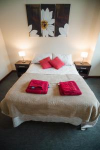 a bedroom with a bed with two red pillows on it at Departamento Ideal in Ushuaia