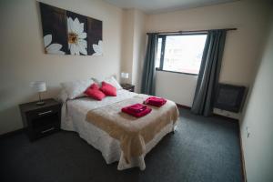 a bedroom with a bed with red pillows and a window at Departamento Ideal in Ushuaia