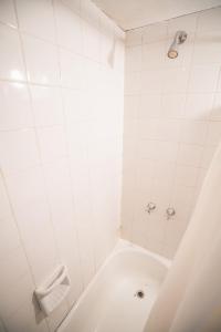 a white tiled bathroom with a bath tub at Departamento Ideal in Ushuaia +12 photos
