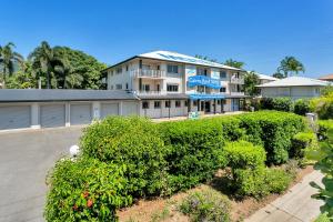 Cairns Reef Apartments & Motel في كيرنز: مبنى فيه شجيرات امام مواقف السيارات