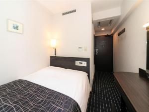 a hotel room with a bed and a night stand at APA Hotel Tennoji-Ekimae in Osaka