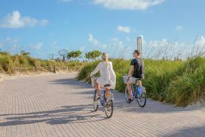 Un uomo e una donna che vanno in bicicletta lungo la strada di Ocean Beach Hotel a Miami Beach