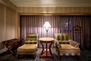 台北的住宿－台北唯客樂飯店，一间设有两把椅子、一张桌子和一盏灯的房间