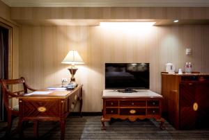 台北的住宿－台北唯客樂飯店，客房设有书桌、电视和灯具。