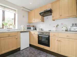 a kitchen with wooden cabinets and a stove top oven at Stonegarth Cottage in Penrith