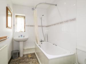 彭里斯的住宿－Stonegarth Cottage，白色的浴室设有浴缸和水槽。