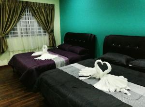 dois cisnes estão sentados em duas camas num quarto em Leisure homestay@Kota Kinabalu em Kota Kinabalu