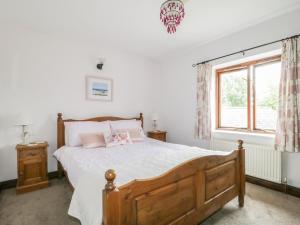 a bedroom with a wooden bed and a window at Stonegarth Cottage in Penrith