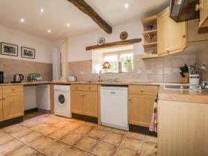 a large kitchen with wooden cabinets and a washer and dryer at Springarth Cottage in Morland