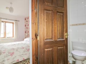a bathroom with a wooden door and a bedroom with a bed at Springarth Cottage in Morland