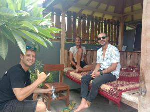 drie mannen zitten op bedden op een veranda bij Sunrise Banyuwangi Homestay in Banyuwangi