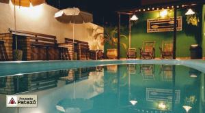 a swimming pool with chairs and an umbrella at Pousada Pataxó in Ubatuba