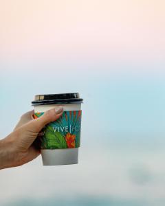 uma mão segurando uma xícara de café no céu em VIVE Hotel Waikiki em Honolulu