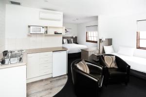 a kitchen with two beds and two chairs in a room at Bay Hotel Apartments in Hobart