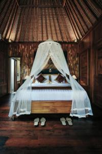 a bedroom with a bed with a mosquito net at KERAMAN SUITE UBUD in Ubud