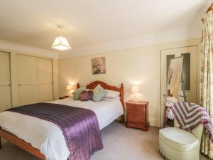 a bedroom with a large bed and a chair at Sea Breeze Cottage in Buckie