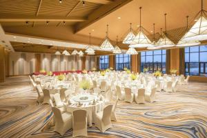 un gran salón de banquetes con mesas y sillas blancas en Holiday Inn Kunshan Huaqiao, an IHG Hotel, en Kunshan