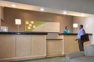 two people standing at a counter in a hotel lobby at Holiday Inn Lumberton by IHG in Lumberton