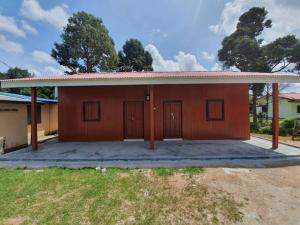 uma pequena casa castanha com garagem em Ikhlas Roomstay em Kampong Alor Gajah