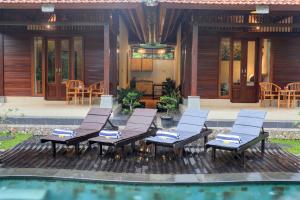 un patio con sillas y una piscina frente a una casa en Pondok Chandani Suite, en Tampaksiring
