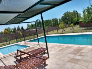 a wooden bench sitting next to a swimming pool at Lucy Sol Cabañas in San Rafael