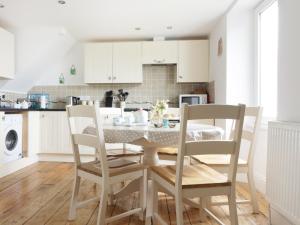 cocina blanca con mesa y sillas en 4 Coastguard Cottages en Coverack