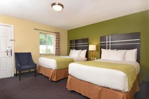 um quarto de hotel com duas camas e uma cadeira em Ardsley Acres Hotel Court em Ardsley