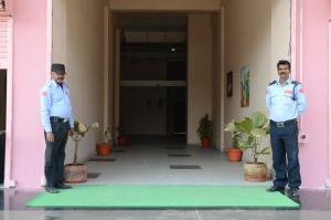 dwóch mężczyzn w mundurach stojących przed różowym budynkiem w obiekcie Namastay Welcome Home -Gaya w mieście Gaja