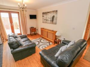 a living room with a leather couch and a television at The Dairy in Llanmorlais