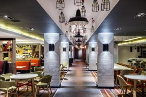 un restaurante con columnas blancas, mesas y sillas en Holiday Inn London Watford Junction, an IHG Hotel, en Watford