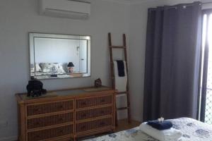 a bedroom with a dresser with a mirror on it at Oceanview Apartment in Airlie Beach