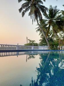 a swimming pool with palm trees and a fence at Rendezvous Place- Luxurious apartment in Varca