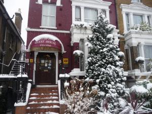 un bâtiment avec un arbre de Noël recouvert de neige devant lui dans l'établissement Crompton Guest House, à Hounslow