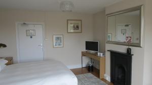 a bedroom with a bed and a television and a fireplace at The Lion Waddesdon in Waddesdon