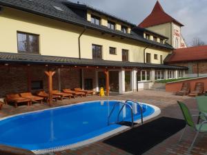 a swimming pool in front of a building with a house at Wellness Hotel Fridrich in Horní Těrlicko