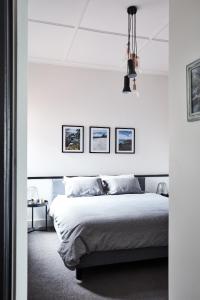 a white bedroom with a bed and three pictures on the wall at St Kilda Beachfront Penthouse in Melbourne