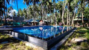 a swimming pool with palm trees in the background at Sea Shell Resort & Spa, Havelock in Havelock Island