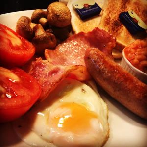 ein Frühstücksteller mit Eiern, Speck, Tomaten und Toast in der Unterkunft The Lion Waddesdon in Waddesdon