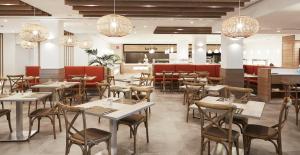 a dining room with tables and chairs and chandeliers at Insotel Club Tarida Playa in Cala Tarida