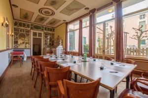 a dining room with tables and chairs and windows at Hôtel Pedussaut in Saint-Gaudens