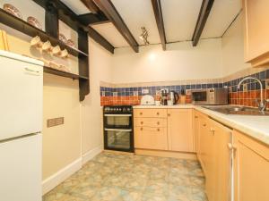 a small kitchen with wooden cabinets and appliances at Mill Cottage in Tintagel