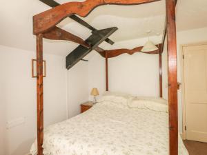 a bedroom with a wooden canopy bed in a room at Mill Cottage in Tintagel