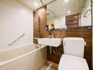 
a bathroom with a toilet, tub, sink and shower at HOTEL MYSTAYS Aomori Station in Aomori
