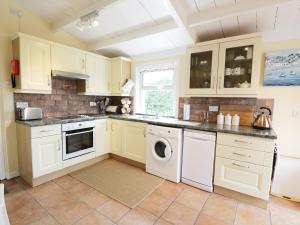 a kitchen with white cabinets and a washer and dryer at Drumbuie in Kirkbean