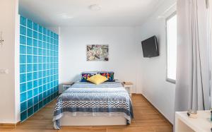 - une chambre avec un lit et un mur carrelé bleu dans l'établissement Ampuries Delta Apartment, à Empuriabrava